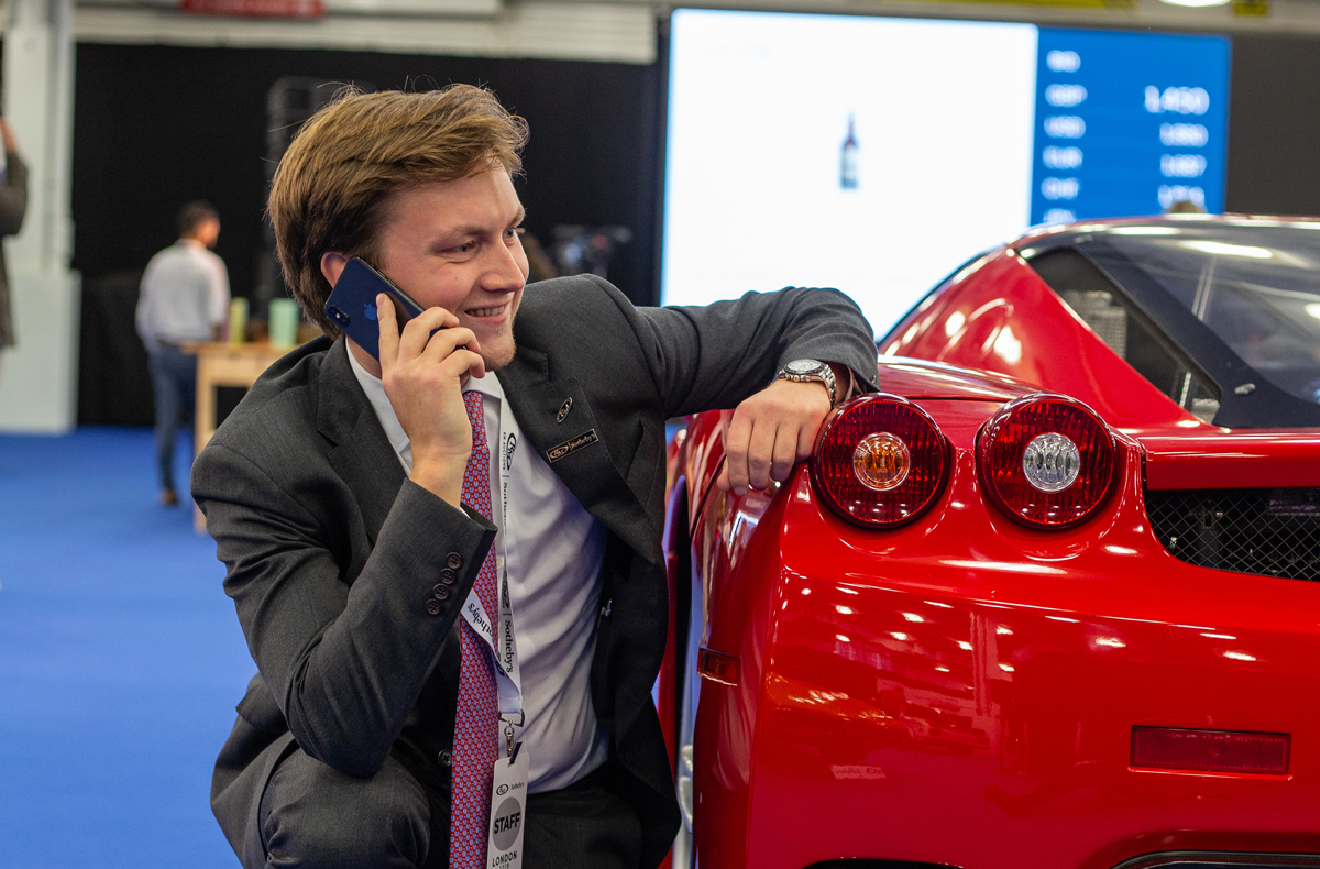 RM Sotheby’s Car Specialist Stephan Knobloch crouching behind a 2003 Ferrari Enzo at London Fall 2019