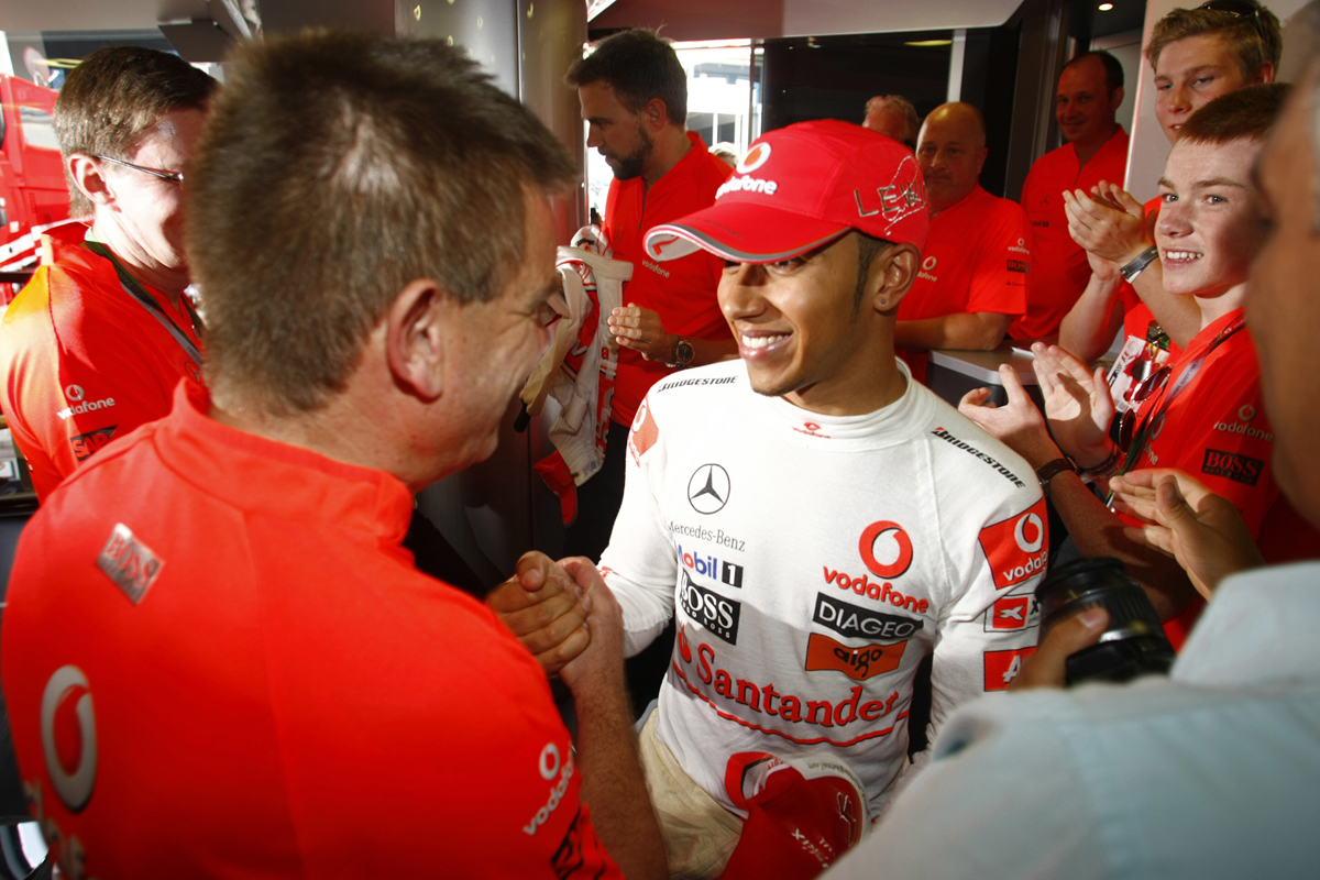 Formula One Race Car Driver Lewis Hamilton shaking hands with a member of his crew at a Formula One event